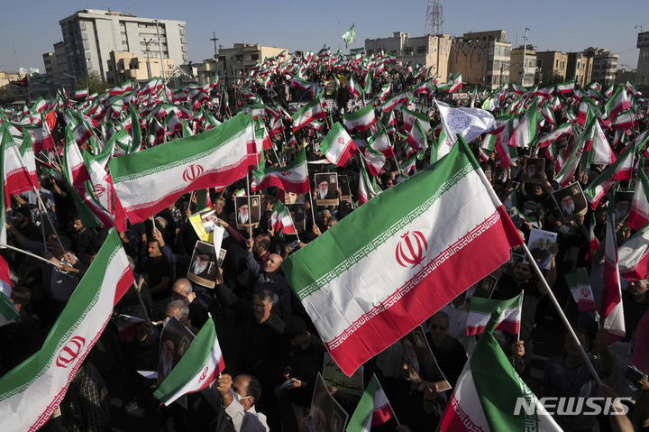 [테헤란=AP/뉴시스] 25일(현지시간) 이란 테헤란에서 친정부 시위대가 반정부 시위대를 규탄하는 맞불 시위를 하면서 국기를 흔들고 있다. 반정부 시위대는 히잡 미착용으로 경찰에 구금됐다가 숨진 22세 쿠르드족 여성의 죽음에 대한 진상 규명을 요구하며 시위를 이어가고 있다. 2022.09.26. 