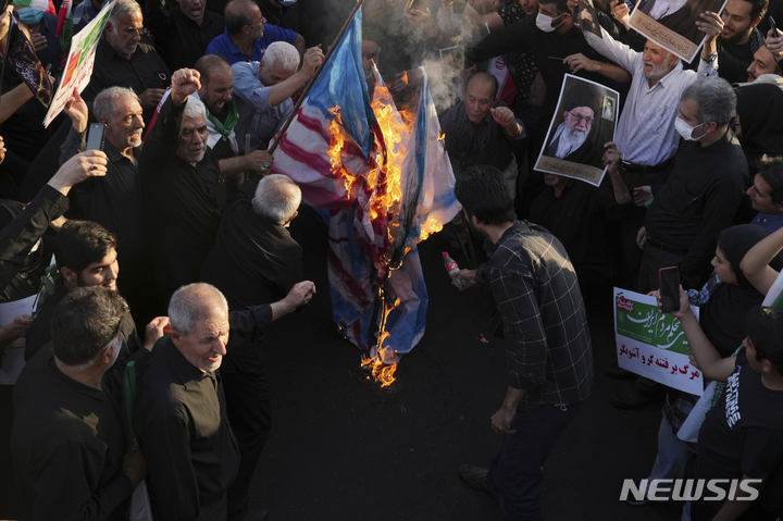 [테헤란=AP/뉴시스] 25일(현지시간) 이란 테헤란에서 친정부 시위대가 반정부 시위대를 규탄하는 맞불 시위를 하면서 영국, 이스라엘, 미국 국기 등을 태우고 있다. 반정부 시위대는 히잡 미착용으로 경찰에 구금됐다가 숨진 22세 쿠르드족 여성의 죽음에 대한 진상 규명을 요구하며 시위를 이어가고 있다. 2022.09.26. 