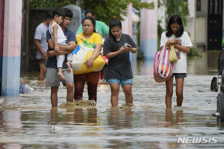 [산미구엘(필리핀)=AP/뉴시스]26일 필리핀 불라칸주 산미구엘 마을에서 태풍 노루로 인한 홍수로 한 가족이 높은 곳으로 대피하고 있다.2022.09.26.