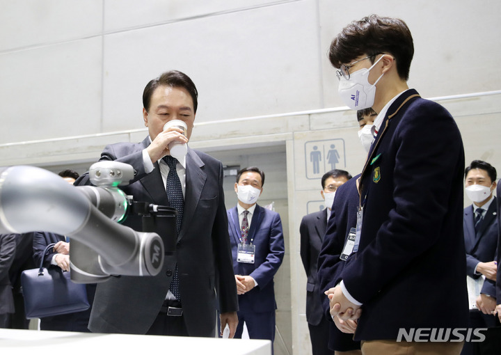 [광주=뉴시스] 전신 기자 = 윤석열 대통령이 28일 광주 서구 김대중컨벤션센터에서 열린 제8차 비상경제 민생회의에 앞서 인공지능 전시회 '2022 AI TECH+'를 찾아 AI교육 선도학교인 조선대부속고등학교 학생들이 개발한 로봇 팔 활용 커피제작 시연을 지켜본 후 로봇이 전달한 커피를 마시고 있다. 2022.09.28. photo1006@newsis.com
