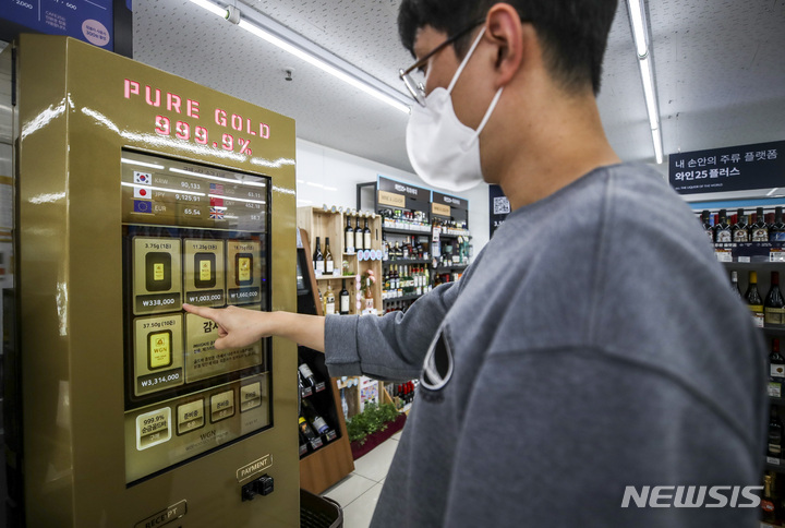 [서울=뉴시스] 정병혁 기자 = 28일 오후 서울 강남구 GS25 역삼홍인점을 찾은 한 시민이 금 자판기를 이용하고 있다. GS리테일은 편의점 GS25와 슈퍼마켓 GS더프레시 5곳에 골드바 등을 판매할 수 있는 금 자판기를 도입해 시험 운영한다고 밝혔다. 매장에서 볼 수 있는 금 자판기는 우수골드네트워크가 개발한 '국민30골드'다. 자판기를 통해 구매할 수 있는 금은 골드바부터 기념주화까지 형태가 다양하다. 중량 또한 1.875g부터 75g까지 5종으로 나뉘어있다. 가격은 국제 금 시세가 반영돼 매일 변경된다. 2022.09.28. jhope@newsis.com