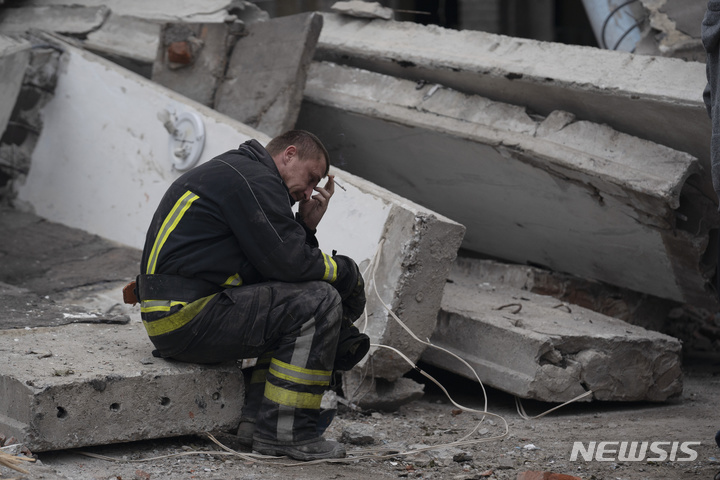 [미콜라이우카=AP/뉴시스] 28일(현지시간) 우크라이나 미콜라이우카의 한 학교가 러시아군의 공격으로 파괴돼 실종자 수색 작업을 하던 한 구조대원이 숨진 여성의 시신이 발견된 현장에서 침통한 표정으로 담배를 피우고 있다. 2022.09.29.