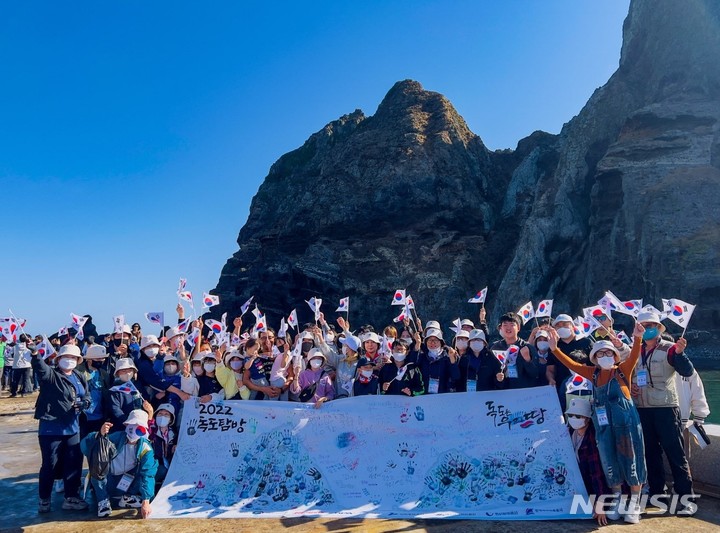 [독도=뉴시스] '아름다운 우리 땅 2022년도 독도탐방' 참가자들이 손도장이 찍힌 대형 독도기를 펼치고 기념사진을 찍고 있는 모습. 