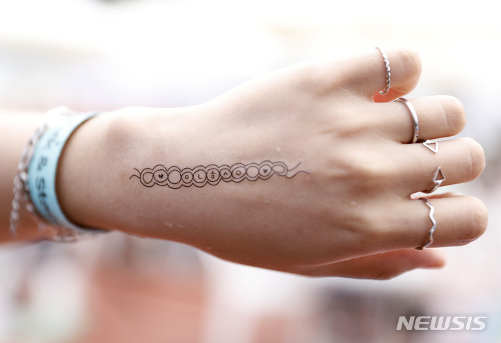 [서울=뉴시스] 고승민 기자 = 2일 서울 잠실종합운동장 보조경기장에서 열린 2022 한국문화축제 더케이 팬페어를 찾은 외국인 참가자들이 한글 타투를 체험하고 있다. 2022.10.02. kkssmm99@newsis.com