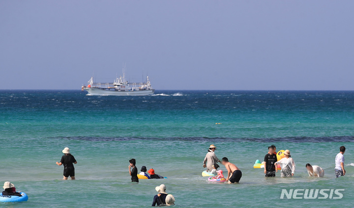 [제주=뉴시스] 우장호 기자 = 낮 최고기온이 30도에 육박하는 무더운 날씨를 보인 3일 오후 제주시 한림읍 협재해수욕장을 찾은 관광객들이 물놀이를 하며 더위를 식히고 있다. 2022.10.03. woo1223@newsis.com
