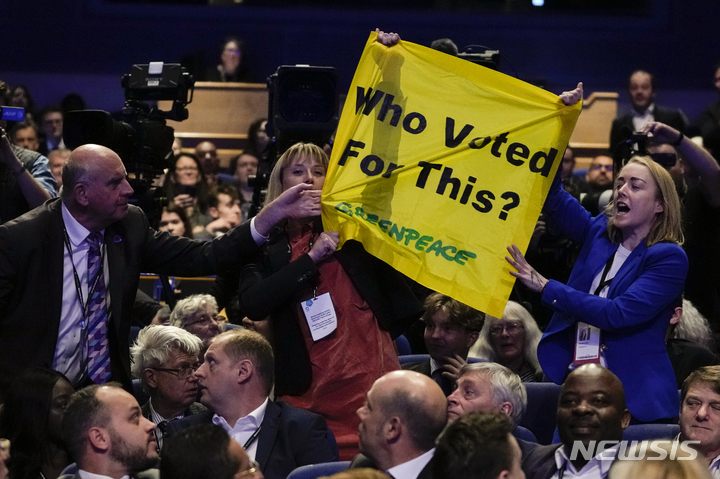 [버밍엄=AP/뉴시스] 5일(현지시간) 잉글랜드 버밍엄 ICC에서 열린 영국 보수당 전당대회에서 리즈 트러스 총리가 연설하는 동안 돌발 시위를 한 환경단체 회원들의 현수막을 한 남성이 잡아 당겨 내리려 하고 있다. 2022.10.06.