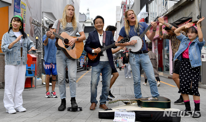 [광주=뉴시스] 이영주 기자 = 제19회 추억의 광주 충장 월드페스티벌과 제1회 버스킹 월드컵 개막 사흘을 앞둔 10일 오전 광주 동구 충장로우체국 앞에서 임택 동구청장(사진 중앙)과 캐나다 밴드 더 브라더스 허니웰(The Brothers Honeywell)이 축제를 홍보하는 거리공연을 펼치고 있다. 2022.10.10. leeyj2578@newsis.com