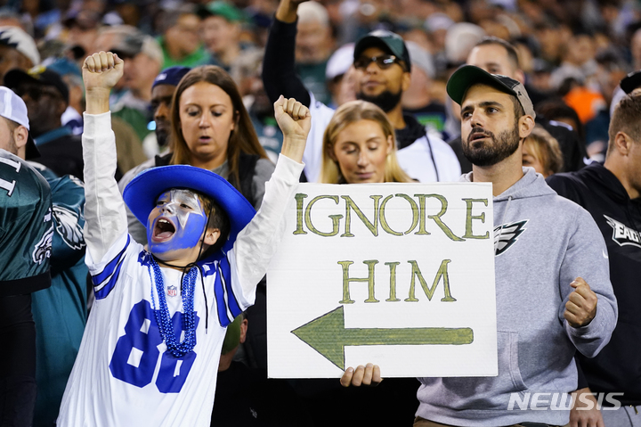 [필라델피아=AP/뉴시스] 필라델피아 이글스의 한 팬이 16일(현지시간) 미 펜실베이니아주 필라델피아의 링컨 파이낸셜 필드에서 열린 미국프로풋볼(NFL) 댈러스 카우보이와의 경기를 관람하면서 댈러스를 응원하는 소년 팬을 무시하라는 팻말을 들고 있다. 2022.10.17.