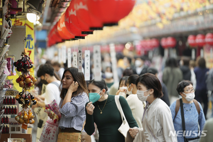 [도쿄=AP/뉴시스]지난 17일 일본 도쿄 아사쿠사에 있는 유명 사찰 센소지 인근 기념품 가게에서 외국인 관광객들이 쇼핑하는 모습. 2022.10.21.