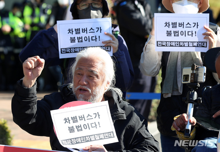 [서울=뉴시스] 이영환 기자 = 박경석 전국장애인차별철폐연대(전장연) 대표가 18일 오전 서울 서초구 서울중앙지방법원 앞에서 버스운행 방해 혐의 재판 선고에 앞서 기자회견을 열고 구호를 외치고 있다. 박 대표는 지난 2021년 4월 8일 마로니에 공원 버스정류장 앞에서 160번 노선버스가 정류장에 정차하자 승차를 요구하였고, 버스기사는 "휠체어를 탄 장애인은 버스를 탈 수 없다"며 탑승을 거부했다. 이 과정에서 박 대표는 15분간 왜 이 버스를 탈 수 없는가에 대한 발언을 하였고 이에 검찰은 신고하지 않은 집회를 개최해 위력으로 버스의 운행을 방해하였다고 징역 6개월을 구형했다. 2022.10.18. 20hwan@newsis.com