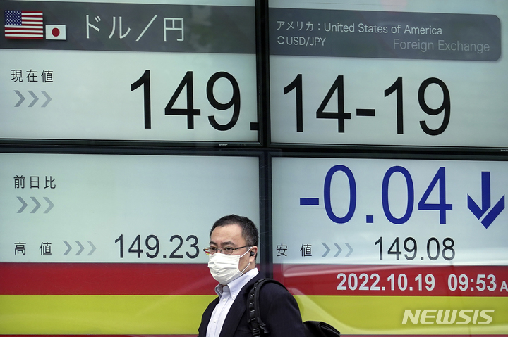 [도쿄=AP/뉴시스]마스크를 쓴 한 시민이 엔·달러 환율이 표시된 도쿄의 한 증권 회사 전자 게시판 앞을 지나가고 있다. 2022.10.21.