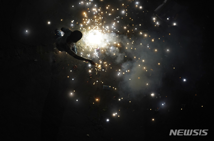 [인도=AP/뉴시스] 한 소년이 24일(현지시간) 인도에서 열린 힌두교 최대 축제인 디왈리를 기념해 폭죽에 불을 붙이고 있다. 2022.10.25.