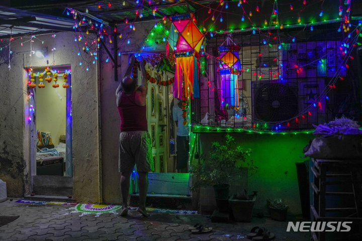 [인도=AP/뉴시스] 디왈리 축제 기간인 24일(현지시간) 인도 뭄바이에서 한 시민이 조명을 달고 있다. 2022.10.25.