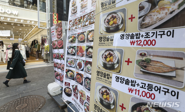[서울=뉴시스] 김근수 기자 = 연일 외식 식재료 가격이 상승한 가운데 26일 오후 서울 중구 명동거리의 음식점 메뉴 안내문 옆으로 관광객이 지나가고 있다. 2022.10.26. ks@newsis.com