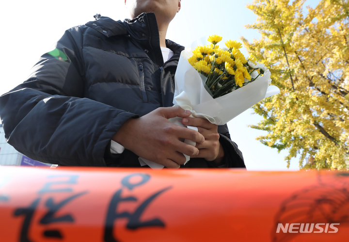 [서울=뉴시스] 김금보 기자 = 30일 오후 서울 용산구 이태원 압사 사고 현장에서 한 시민이 근조화를 들고 추모 공간 마련을 기다리고 있다.  2022.10.30. kgb@newsis.com