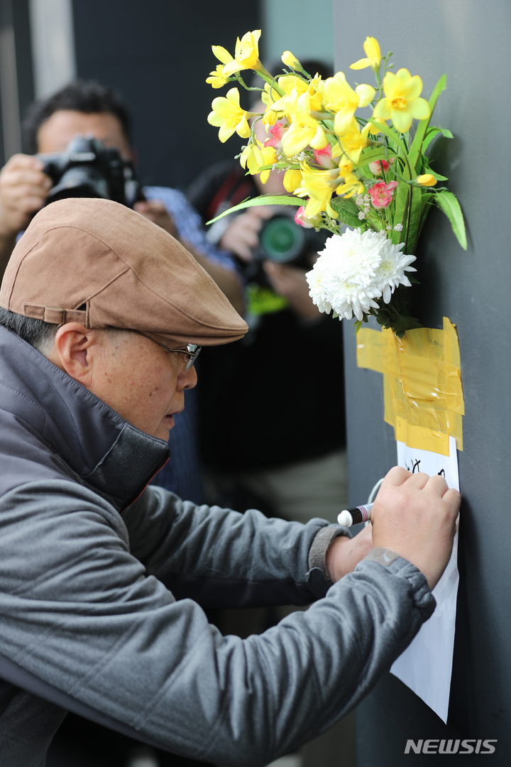[서울=뉴시스] 김금보 기자 = 30일 오후 서울 용산구 이태원 할로윈 참사 현장 인근 건물 외벽에 한 시민이 근조화를 부착하고 애도하고 있다. 2022.10.25. kgb@newsis.com