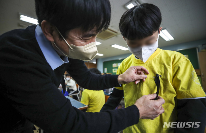 [서울=뉴시스] 정병혁 기자 = 지난 1일 오전 서울 용산구 한 초등학교에서 담임선생님이 한 학생 가슴에 검은색 리본을 달아주고 있다. 2022.11.02. jhope@newsis.com