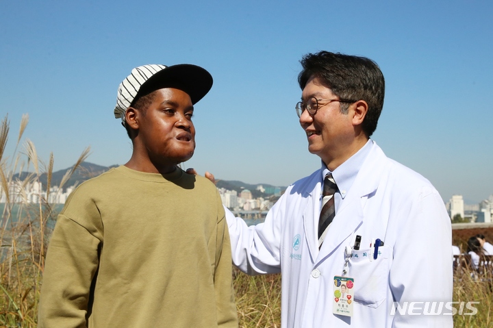 [서울=뉴시스]한국을 찾아 얼굴 크기만 한 종양을 성공적으로 치료받은 마다가스카르 청년 플란지에게 수술을 집도한 최종우 서울아산병원 성형외과 교수가 귀국을 앞두고 덕담을 건네고 있다. (사진= 서울아산병원 제공) 2022.11.03
