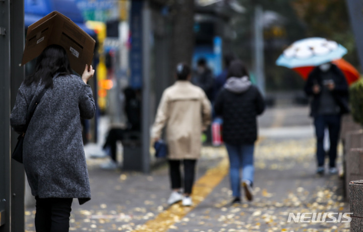 [서울=뉴시스] 정병혁 기자 = 15일 오후 서울 중구 명동에서 갑자기 내린 소나기에 한 시민이 박스를 머리에 쓰고 비를 피하고 있다. 2022.11.15. jhope@newsis.com
