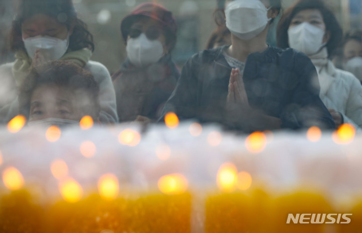 [서울=뉴시스] 조수정 기자 = 2023학년도 대학수학능력시험일인 17일 오전 서울 종로구 조계사에서 수능 고득점 기원 초 너머로 학부모들이 고득점 기원 법회에 참여해 합장하고 있다. 2022.11.17. chocrystal@newsis.com