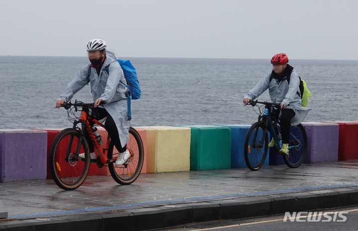 [제주=뉴시스] 오영재 기자 = 제주 용담동 해안도로에서 관광객들이 우비를 입은 채 자전거를 타고 있다. (뉴시스DB) oyj4343@newsis.com
