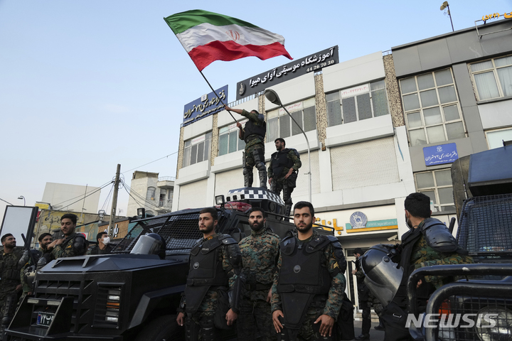 [테헤란(이란)= 뉴시스] 이란 월드컵 축구 국가대표팀이 25일 웨일즈와의 경기에서 승리한 뒤 테헤란 시내의 시위진압경찰대중 한 명이 이란 국기를 휘두르며 축하하고 있다. 이란은 곳곳의 시위를 진압하는 한 편 남부 후지스탄 주 등 지역에서 무기 밀매조직에 대한 대대적인 경찰 단속을 펴고 있다. 