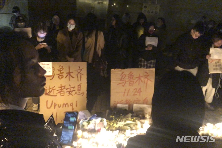 [상하이(중국)=AP/뉴시스] 11월 26일 밤 (현지시간) 중국 상하이 시내의 코로나19봉쇄 반대 시위대가 중국 신장의 한 아파트 화재로 숨진 10명의 영혼을 위로하는 집회를 갖고 있다.