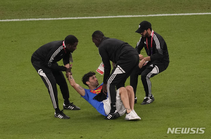 [루사일=AP/뉴시스] 28일(현지시간) 카타르 루사일 스타디움에서 열린 2022 카타르 월드컵 조별리그 H조 2차전 포르투갈과 우루과이의 경기 중 '우크라이나를 구하자'라고 쓰인 셔츠를 입은 한 남성이 경기장에 난입해 관계자들에게 제지당하고 있다. 2022.11.29.