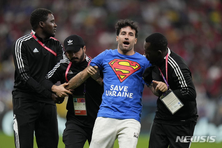 [루사일=AP/뉴시스] 28일(현지시간) 카타르 루사일 스타디움에서 열린 2022 카타르 월드컵 조별리그 H조 2차전 포르투갈과 우루과이의 경기 중 '우크라이나를 구하자'라고 쓰인 셔츠를 입은 한 남성이 경기장에 난입해 관계자들에게 끌려나가고 있다. 2022.11.29.