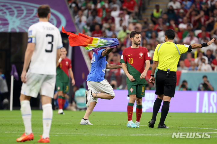 [루사일(카타르)=뉴시스] 백동현 기자 = 28일(현지시간) 카타르 루사일 스타디움에서 열린 2022 카타르 월드컵 조별리그 H조 2차전 포르투갈과 우루과이의 경기, 한 남성이 무지개 색깔의 깃발을 흔들며 경기장에 난입하고 있다. 이 남성이 입은 셔츠 뒤에는 'RESPECT FOR IRANIAN WOMAN'라고 적혀있다. 2022.11.29. livertrent@newsis.com