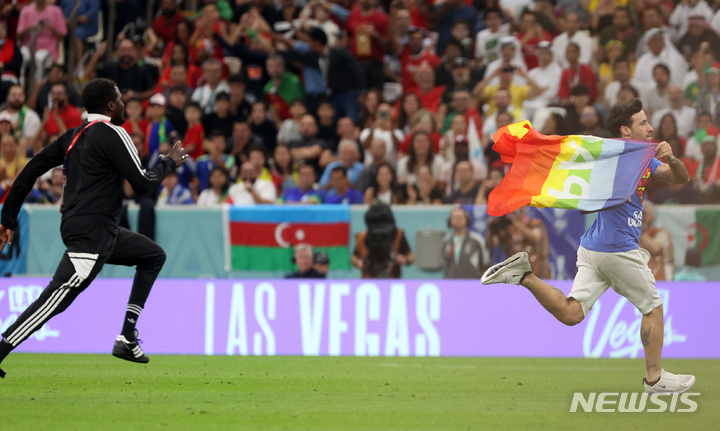 [루사일(카타르)=뉴시스] 백동현 기자 = 28일(현지시간) 카타르 루사일 스타디움에서 열린 2022 카타르 월드컵 조별리그 H조 2차전 포르투갈과 우루과이의 경기, 한 남성이 무지개 색깔의 깃발을 흔들며 경기장에 난입하고 있다. 이 남성이 입은 셔츠 뒤에는 'RESPECT FOR IRANIAN WOMAN'라고 적혀있다. 2022.11.29. livertrent@newsis.com