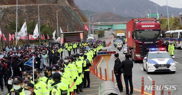 [부산=뉴시스] 하경민 기자 = 민주노총 공공운수노조 화물연대본부 총파업 엿새째인 29일 부산 강서구 부산신항 교차로에서 화물연대 부산본부 조합원들이 총파업 투쟁 승리 결의대회를 열고 거리행진을 펼치고 있는 가운데 경찰 순찰차 등의 에스코트를 받는 화물차가 이동하고 있다. 2022.11.29. yulnetphoto@newsis.com