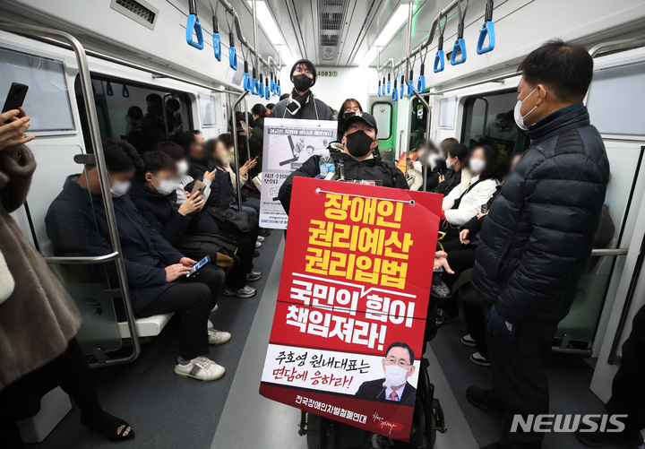 [서울=뉴시스] 김진아 기자 = 전국장애인차별철폐연대 회원들이 30일 오전 서울 용산구 삼각지역 4호선에서 열린 장애인 권리 예산 확보를 위한 지하철 선전전에서 지하철을 타고 있다. 2022.11.30. bluesoda@newsis.com