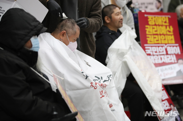 [서울=뉴시스] 김진아 기자 = 전국장애인차별철폐연대 회원들이 30일 오전 서울 용산구 삼각지역 4호선에서 열린 장애인 권리 예산 확보를 위한 지하철 선전전에서 삭발을 하고 있다. 2022.11.30. bluesoda@newsis.com