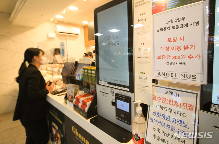 [제주=뉴시스] 우장호 기자 = 2일부터 제주에서 일회용컵에 음료를 받으려면 컵 보증금 300원을 지불해야 한다. 정부는 일회용 폐기물을 줄이기 위해 이날부터 제주와 세종에서 '일회용컵 보증금' 제도를 시범 실시한다. 사진은 보증금제 시행을 알리는 안내문이 게시된 제주국제공항내 프랜차이즈 매장 모습. 2022.12.02. woo1223@newsis.com