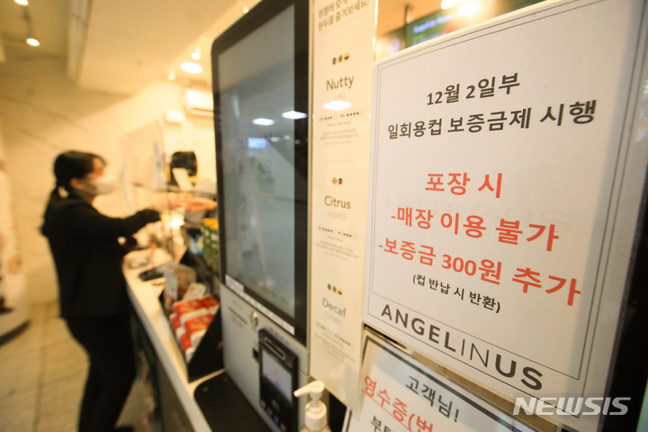 [제주=뉴시스] 우장호 기자 = 지난해 12월2일부터 제주에서 일회용컵에 음료를 받으려면 컵 보증금 300원을 지불해야 한다. 정부는 일회용 폐기물을 줄이기 위해 이날부터 제주와 세종에서 '일회용컵 보증금' 제도를 시범 실시한다. 사진은 보증금제 시행을 알리는 안내문이 게시된 제주국제공항내 프랜차이즈 매장 모습. 2022.12.02. woo1223@newsis.com