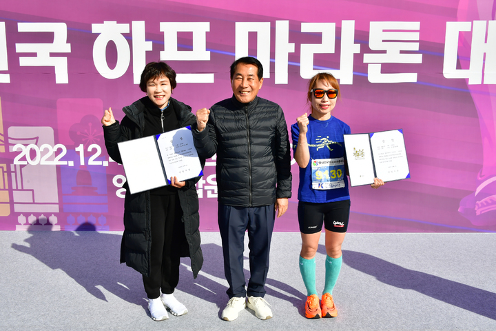[양산=뉴시스] 안지율 기자 = 가족과 함께 겨울을 달리는 제16회 경남 양산전국하프마라톤대회가 4일 양산종합운동장에서 열린 가운데 나동연 시장이 여자 하프코스 우승자와 기념촬영을 하고 있다. 사진 왼쪽부터 2위 권순희, 나동연 시장, 1위 이영아 선수. (사진=양산시 제공) 2022.12.04. photo@newsis.com *재판매 및 DB 금지