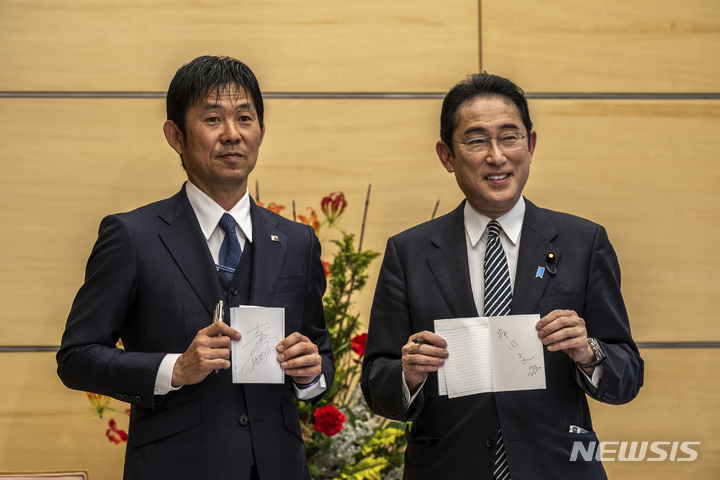 [도쿄=AP/뉴시스] 기시다 후미오(오른쪽) 일본 총리가 8일 도쿄 총리관저에서 일본 축구 대표팀의 모리야스 하지메 감독과 서로의 친필 사인을 교환한 후 기념 촬영을 하고 있다. 2022.12.08. 