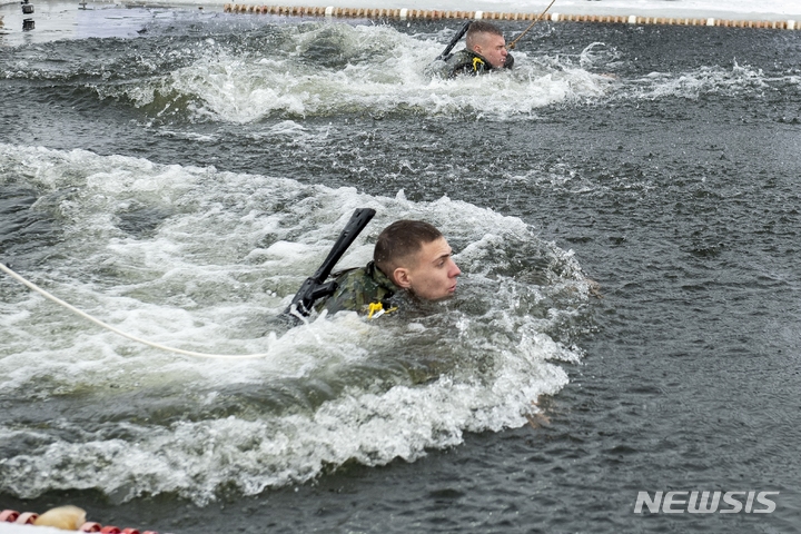 [튜멘(러시아)=AP/뉴시스] 러시아 튜멘군사대학 생도가 지난해 12월11일 영하 8℃의 날씨 속에 AK-47 돌격소총 등 군 장비를 착용하고 차가운 강물에서 동료와 수영을 하며 기록에 도전하고 있다. 사진은 기사 내용과 직접적인 관련이 없다. 2023.05.28.