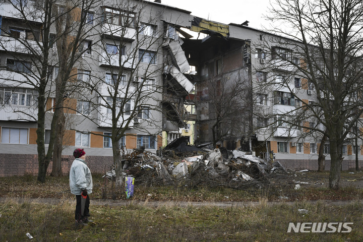 [바흐무트=AP/뉴시스]한 여성이 11일(현지시간) 우크라이나 도네츠크 지역에서 러시아군과 가장 치열한 전투가 벌어졌던 바흐무트에서 러시아군의 포격으로 파손된 아파트 옆을 지나고 있다. 2022.12.12.