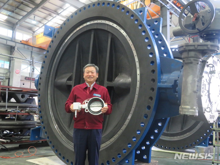 [부산 뉴시스] 이동민 기자 = 세진밸브공업 주력 상품인 버터플라이 밸브를 들고 있는 방영혁 대표. 방 대표 뒤에 있는 버터플라이 밸브는 지름 약 2m로 해외 해수담수화 플랜트사에 납품된다. 2022.12.12. eastsky@newsis.com