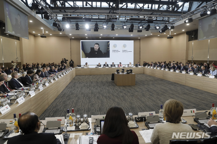 [파리=AP/뉴시스] 볼로디미르 젤렌스키(위) 우크라이나 대통령이 13일(현지시간) 프랑스 파리에서 열린 '우크라이나 국민과의 연대' 국제회의에 화상으로 참여하고 있다. 프랑스 정부는 우크라이나의 인프라 재건 지원을 위해 물자와 자금을 모으는 국제회의를 개최했다. 2022.12.13.