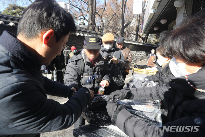 [서울=뉴시스] 권창회 기자 = 강력한 한파를 보인 날 서울 종로구 탑골공원 인근 무료급식소에서 관계자들이 어르신들에게 방한용품을 나누어주고 있다. 2022.12.14. kch0523@newsis.com