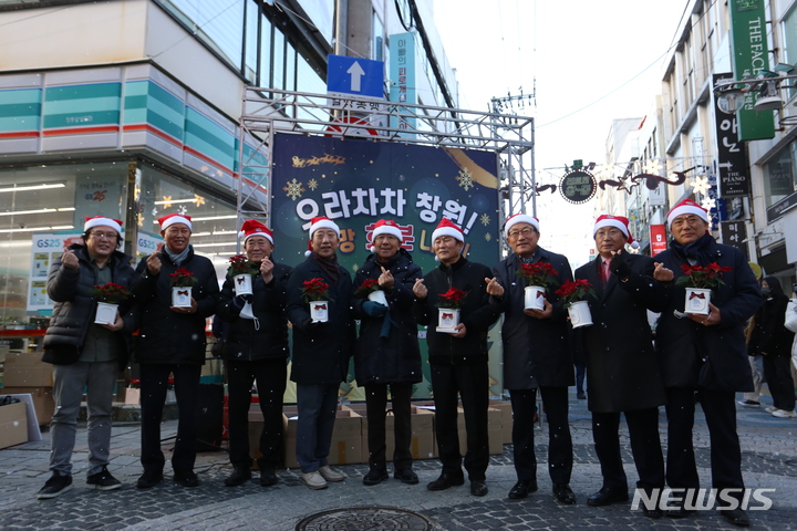 [창원=뉴시스] 홍정명 기자=지난 17일 오후 경남 창원시 마산합포구 창동상가사거리에서 열린 '으라차차 창원! 희망나눔 화분’ 전달식에 참석한 구자천(왼쪽 다섯 번째) 창원상의 회장 등이 기념촬영을 하고 있다.(사진=창원상의 제공)2022.12.18. photo@newsis.com