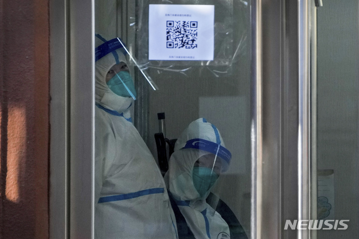 [베이징=AP/뉴시스] 19일 중국 베이징의 한 발열 전담 병원에서 방호복을 입은 의료진이 밖을 내다보고 있다. 중국 국가위생건강위원회는 전날 중국 전역에서 코로나19 감염으로 인한 사망자가 2명 더 늘어났다고 밝혔다. 중국 당국이 '위드 코로나' 정책으로 급전환하면서 코로나19 감염이 급속도로 확산하는 것으로 알려졌다. 2022.12.19.