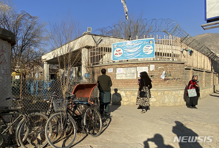 [카불=AP/뉴시스] 21일(현지시간) 아프가니스탄 카불의 카불 대학 정문 옆에서 탈레반 보안 요원이 경비하는 동안 여대생들이 잠시 학교에 들르고 있다. 아프간 탈레반 정권은 전날 공·사립대학교에서의 여학생 수업 참여를 금지한다고 밝혀 애초 여성 인권을 존중하겠다는 약속을 어기고 있다. 2022.12.21.