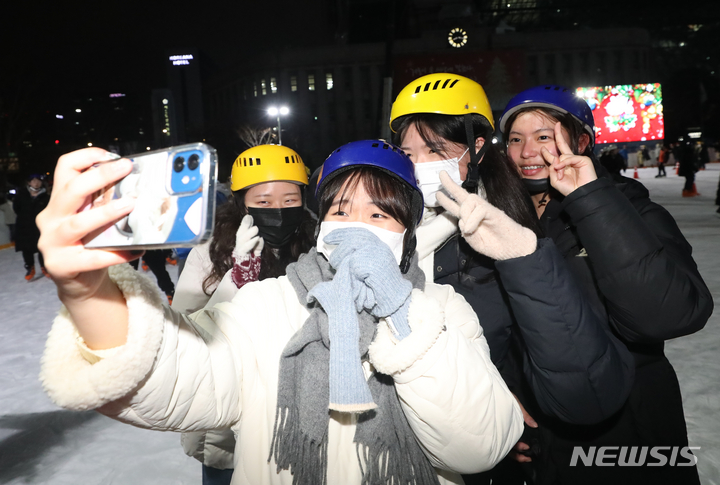 [서울=뉴시스] 김근수 기자 = 서울시청 앞 광장 스케이트장 개장 첫 날인 21일 오후 서울시청 앞 광장에서 시민들이 셀카를 찍고 있다. 서울광장 스케이트장은 코로나19 확산에 따른 사회적 거리두기 시행 이후 3년 만에 다시 개장했다. 서울시는 서울광장 스케이트장을 내년 2월 12일까지 운영한다고 밝혔다. 2022.12.21. ks@newsis.com