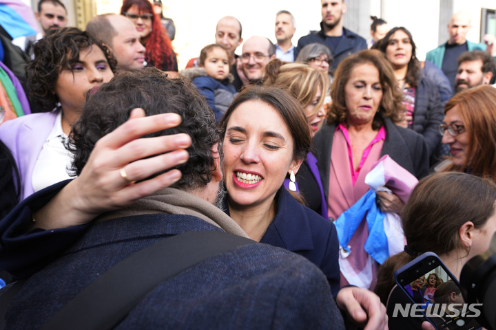 [마드리드=AP/뉴시스] 이레네 몬테로(가운데) 스페인 양성평등부 장관이 22일(현지시간) 마드리드 의회 앞에서&nbsp; 사람들이 성별을 자유롭게 바꾸게 해주는 트랜스젠더 법이 발표된 후 한 시민을 안아주고 있다. 스페인 하원은 16세 이상의 시민이 의료 감독 없이 등록된 성별을 바꿀 수 있도록 하는 성전환 법안을 통과시켰다. 이에 따라 12~13세 미성년자는 성별 변경을 위해 판사의 허가가 필요하고 14~16세 사이의 미성년자는 부모나 법률 대리인과 동행해야 한다. 2022.12.23.
