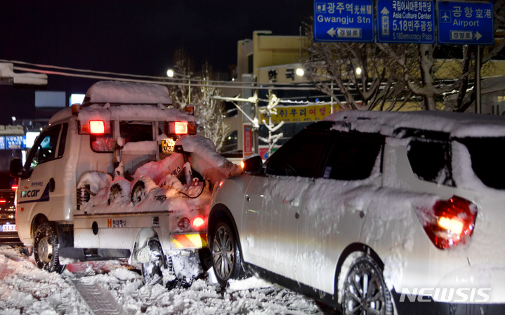 [광주=뉴시스] 이영주 기자 = 광주 지방에 최심적설량 40㎝에 가까운 눈이 내린 23일 오후 광주 동구 한 사거리에서 빙판길에 바퀴가 헛돈 SUV 차량이 견인되고 있다. 2022.12.23. leeyj2578@newsis.com