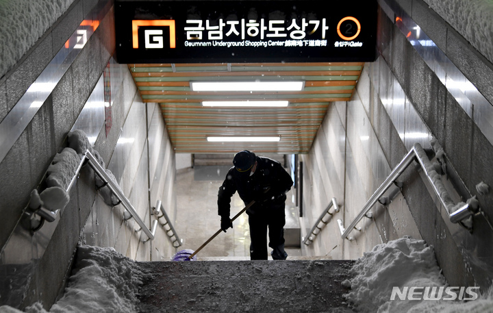 [광주=뉴시스] 이영주 기자 = 광주 동구 금남지하도상가 입구에서 경비원이 눈을 치우고 있다. 2022.12.23. leeyj2578@newsis.com